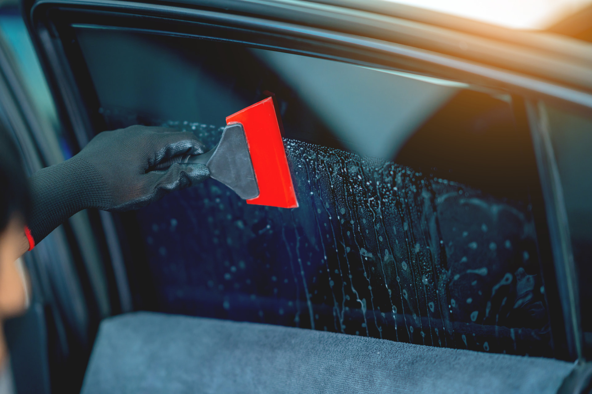 Window film being squeegeed onto a car door glass