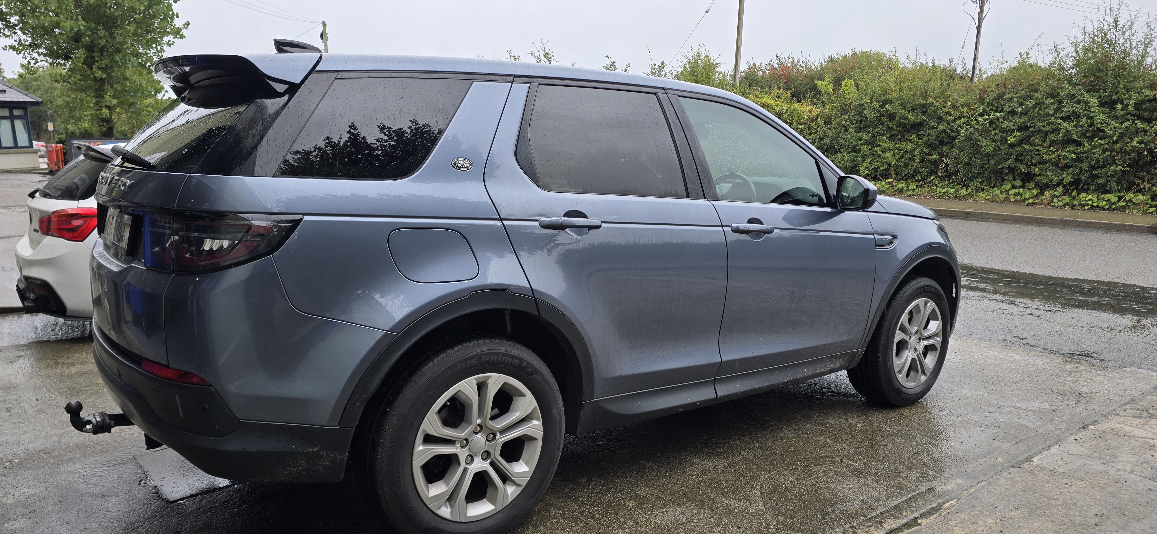 Rear side profile of a grey Land Rover Discovery Sport showing dark tinted rear glass and legal front tint