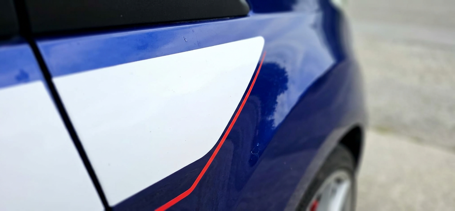 Macro detail of the Transit Connect Sport stripe decal beside freshly tinted glass